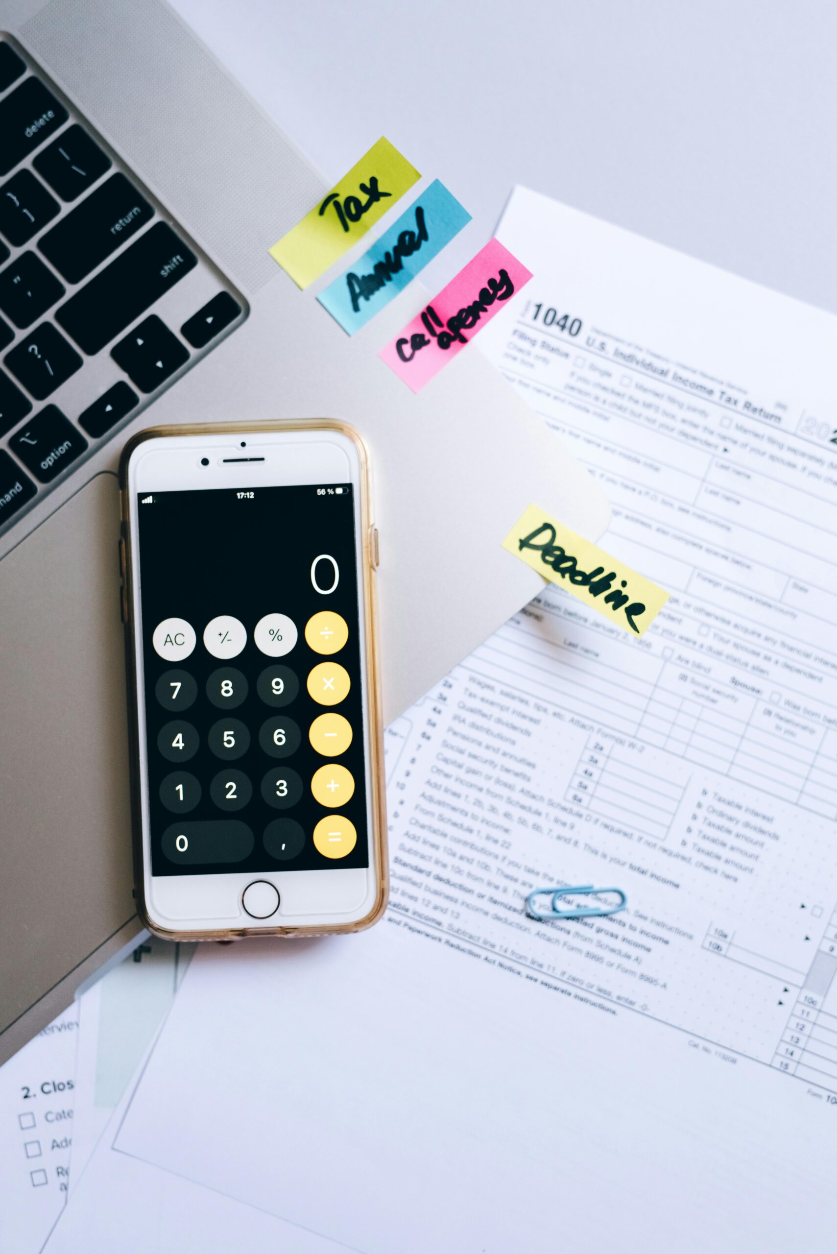 A smartphone calculator and tax forms on a desk, symbolizing financial planning.